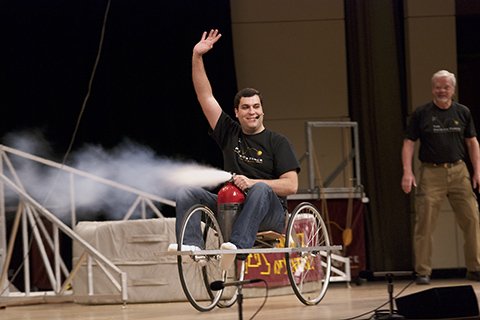 presenter on stage in cart using air to push backwards