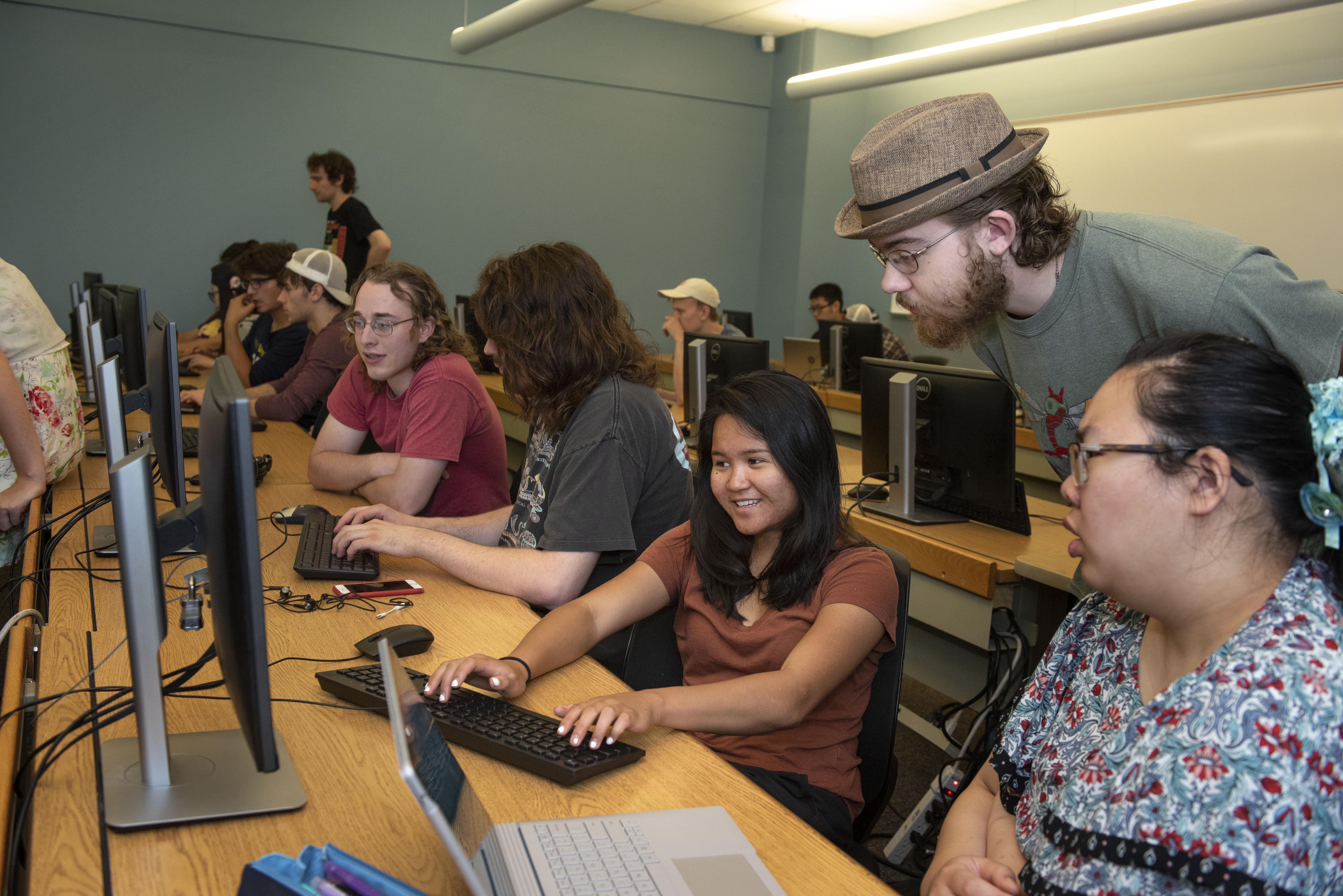 Students work together in a computer lab with faculty helping