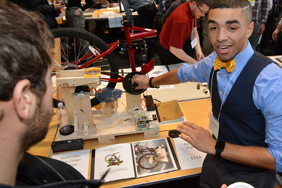 A student demonstrates a robotic bicycle chain cleaner he built at the 2019 Mechanical Engineering Robot Show