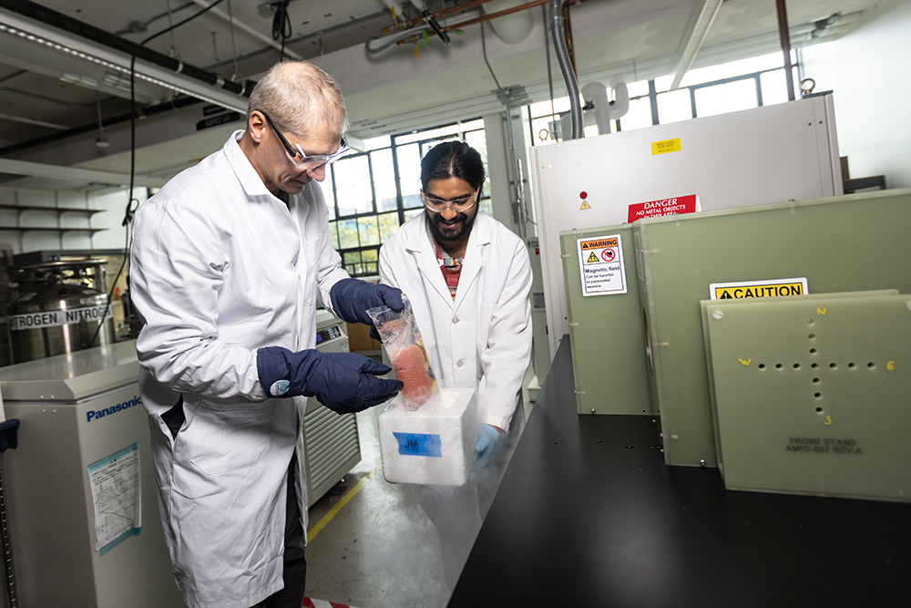 University of Minnesota College of Science and Engineering Professor John Bischof holding cryopreserved tissue samples with mechanical engineering researcher Lakshya Gangwar in front of one-of-a-kind pieces of equipment 