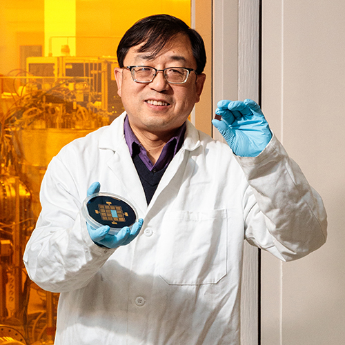 Jian-Ping Wang holding microchip in front of Minnesota Nano Center window