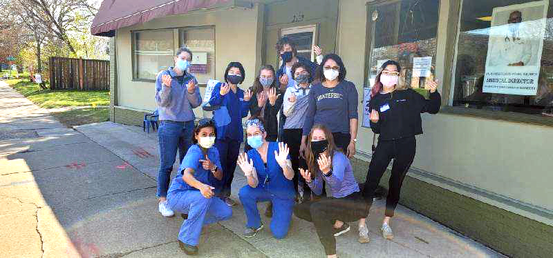 A group of 10 people with masks outside a building. 