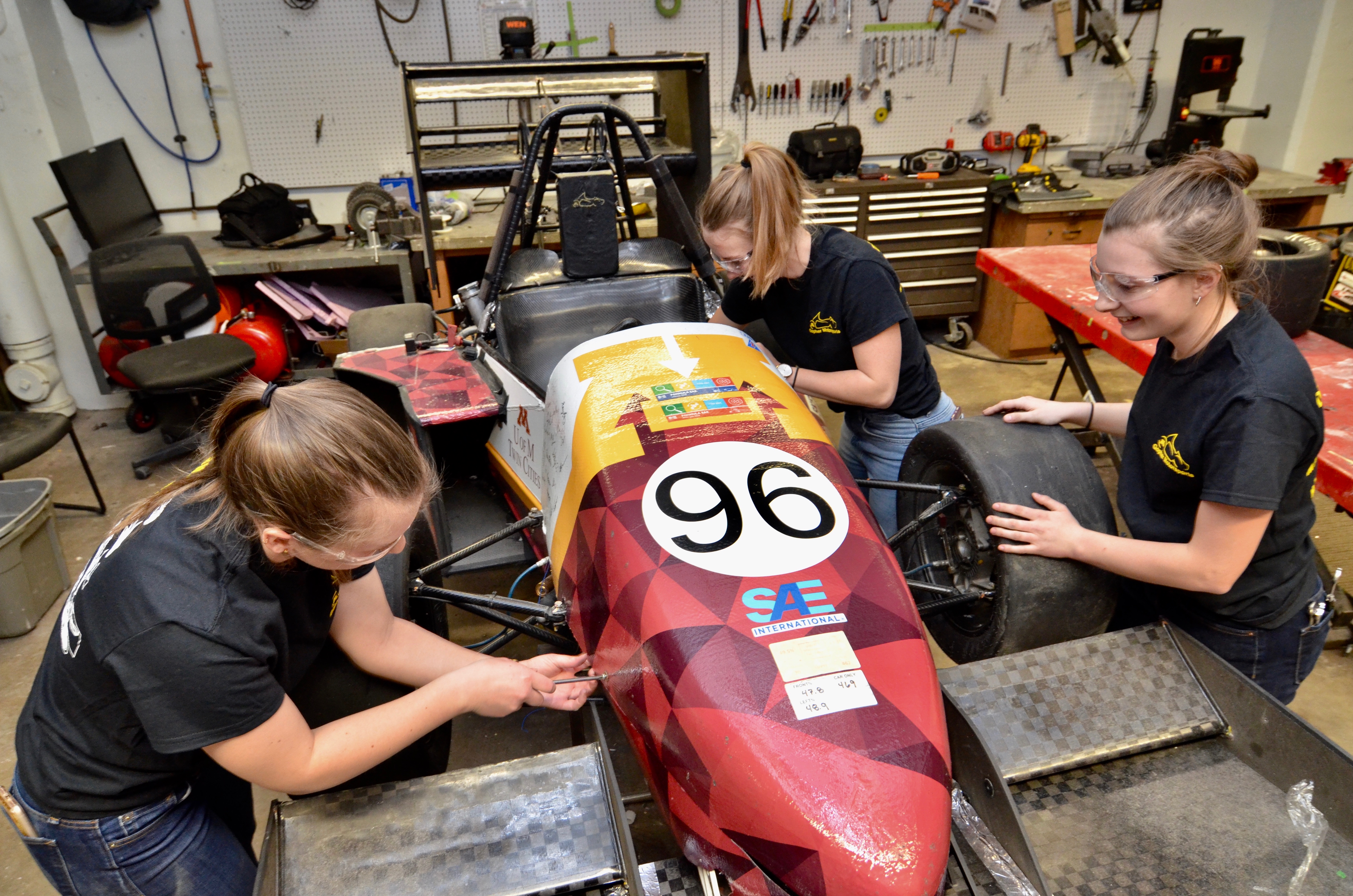 Three students working on a Gopher Motorsports race car