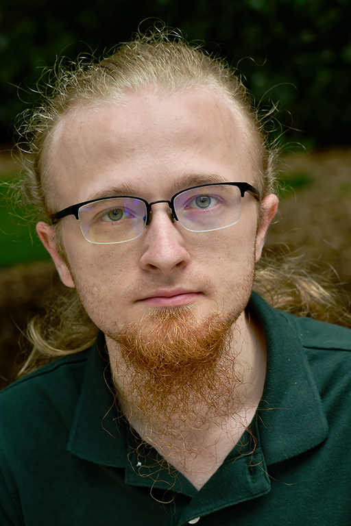 Bearded person with glasses and blond hair