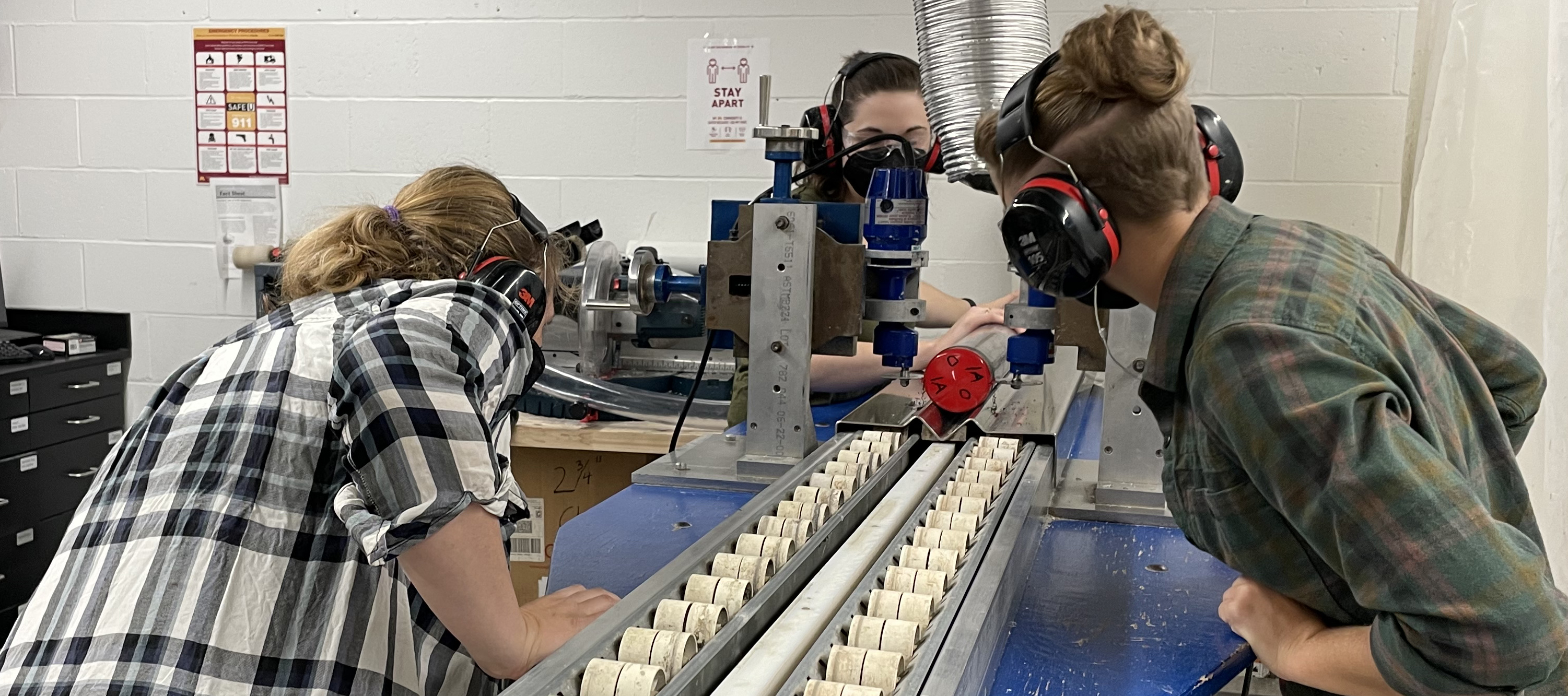 Three female researchers split open a core using cast saws