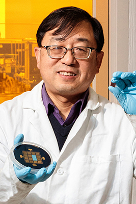 Jian-Ping Wang holding up pietri dish in lab coat