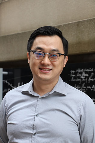Jun Li wearing a blue shirt standing in the scholar's walkway