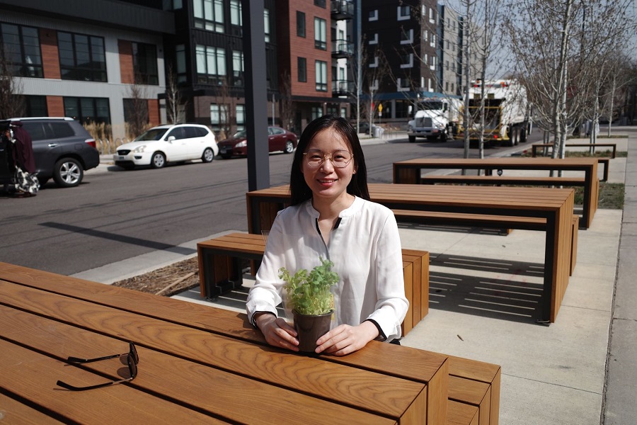 Lulu Ge sitting at an outdoor table holding a plant