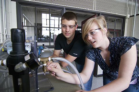 two students looking at machine in mechanical engineering lab