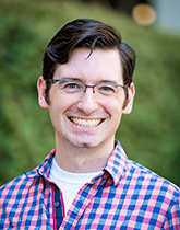 Mike Hill in a checkered shirt, smiling outside