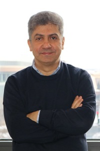 Professor Maddah-Ali in a dark sweater standing with his back to a window