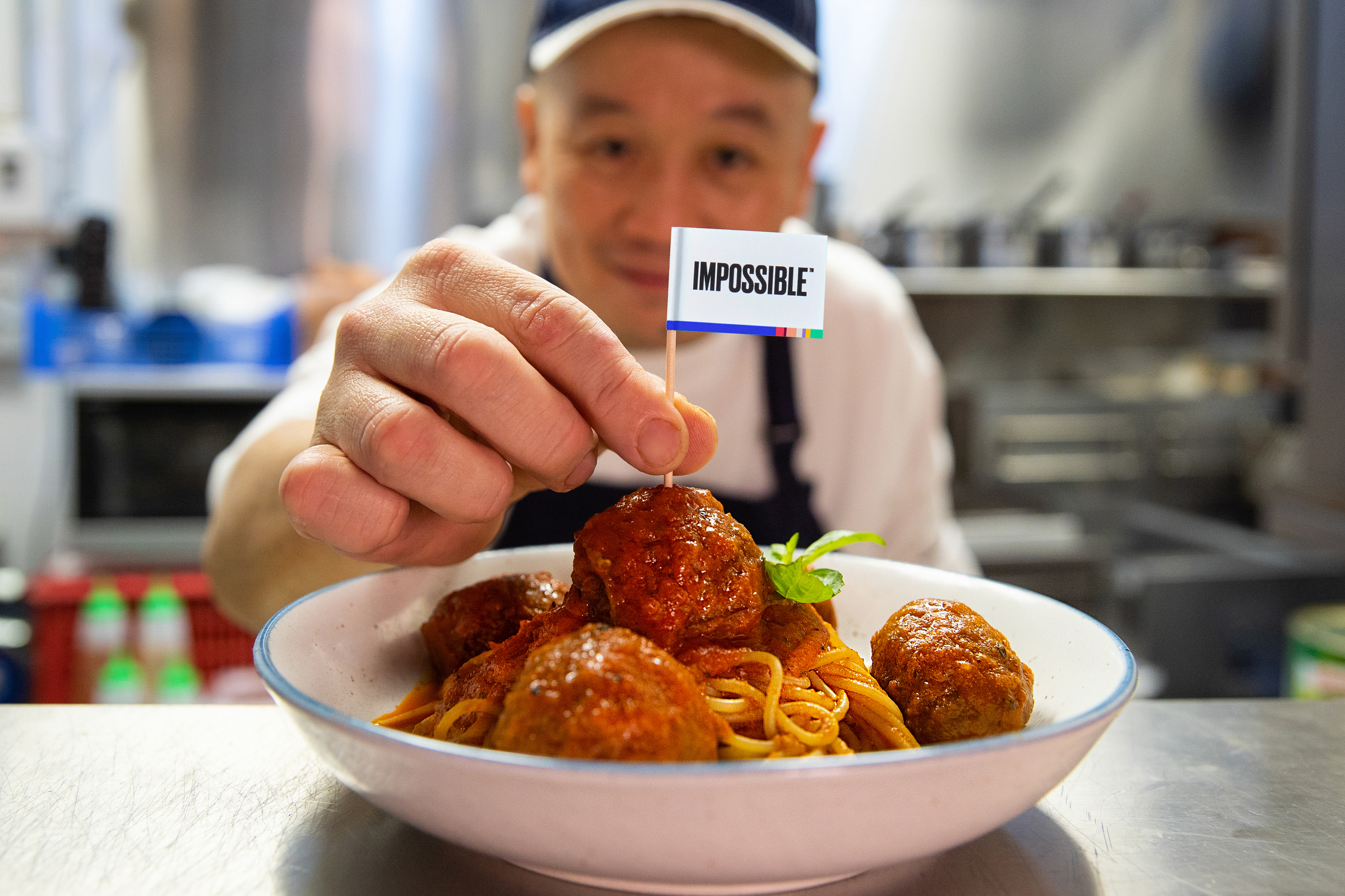A man sticking a mini "Impossible" flag into a meatball.