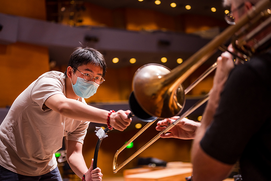 Close-up photo of researchers with trombone player at Orchestra Hall