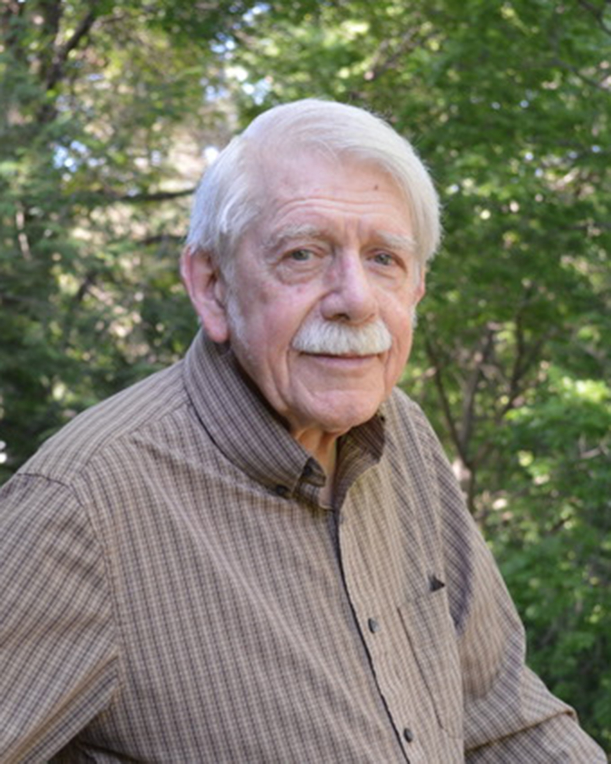 Bob Pepin (man with gray hair and mustache standing in front of trees)