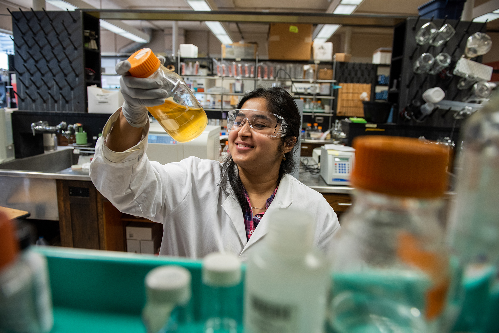 Prakriti Kalra working in lab holding up container