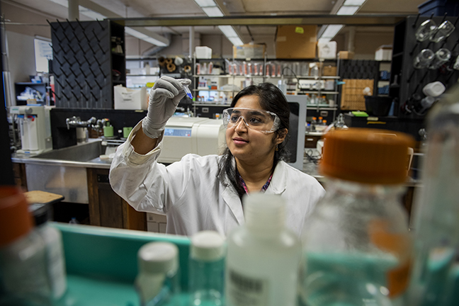 Prakriti Kalra working in the lab holding up tube