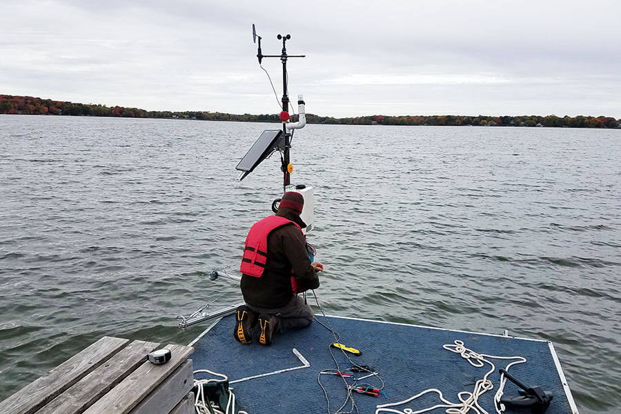 Researcher on lake dock adjusting sensing equipment