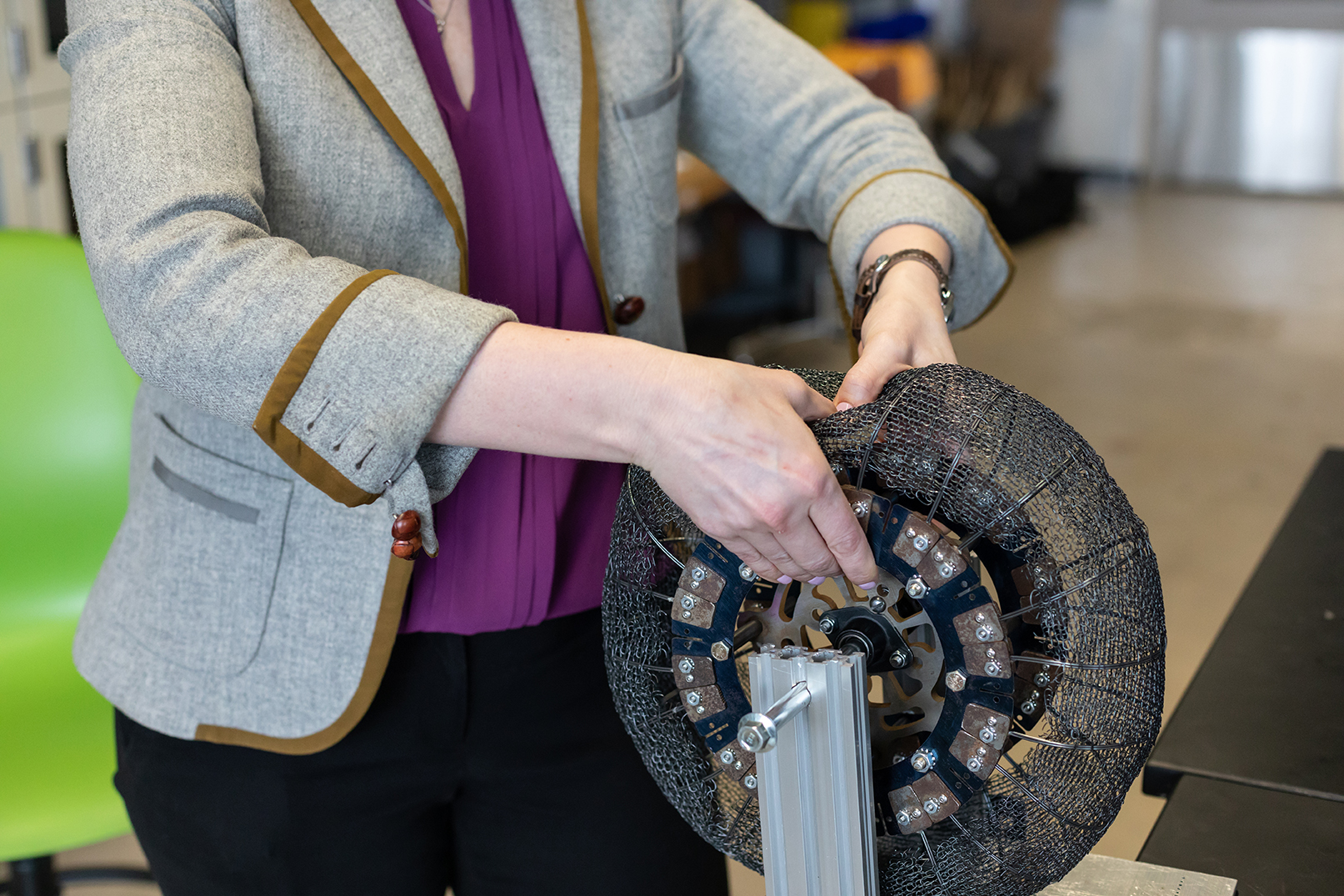 A woman's hands pressing into a tire made of wire.