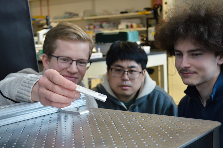 Three students look at an object that has a metamaterial surface.