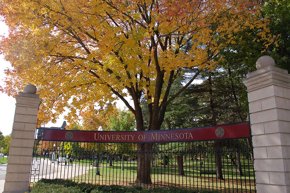 Entry gate with University of Minnesota sign, in front of autumn trees