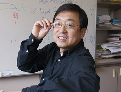 Jian-Ping Wang sitting in front of a white board.