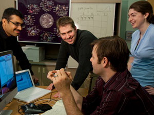 Chad Myers, center, works with graduate students Raamesh Deshpande, left, and Elizabeth Koch, right, and postdoctoral researcher Jeremy Bellay, foreground, on computers