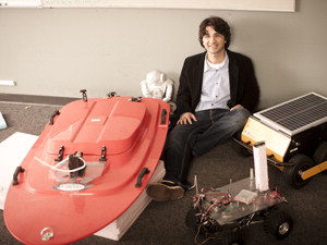 Volkan Isler next to robo boat and other robotics