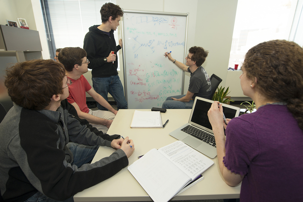 Students in a meeting and writing on a white board