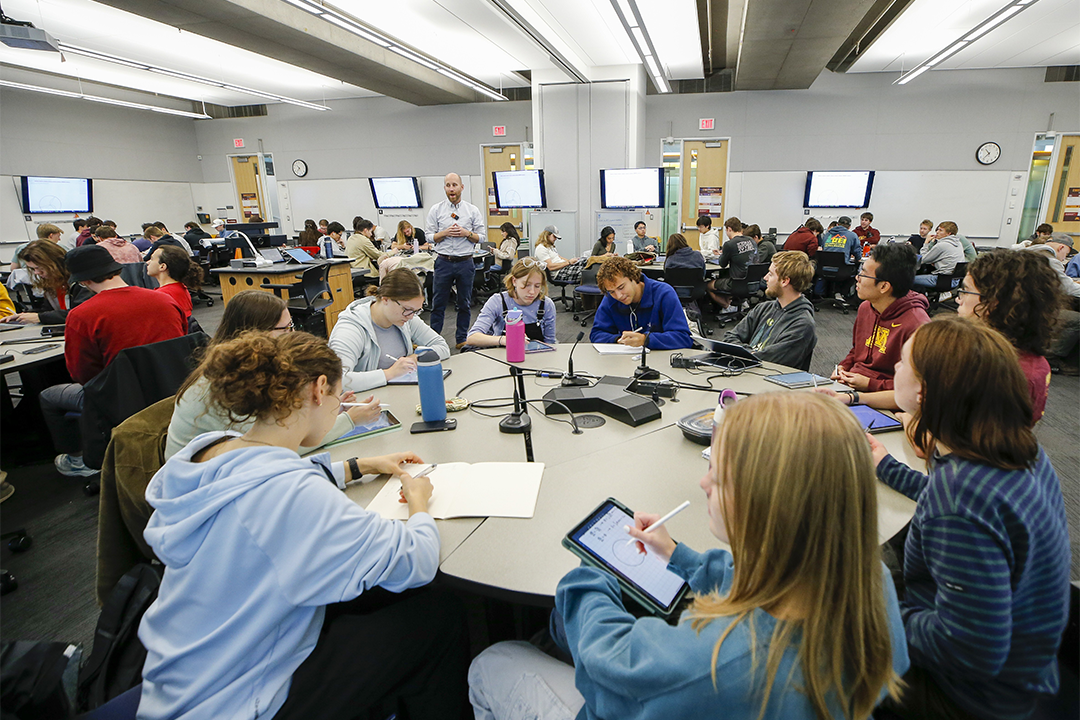 Students working at round tables while an instructor teaches in an active-learning classroom.