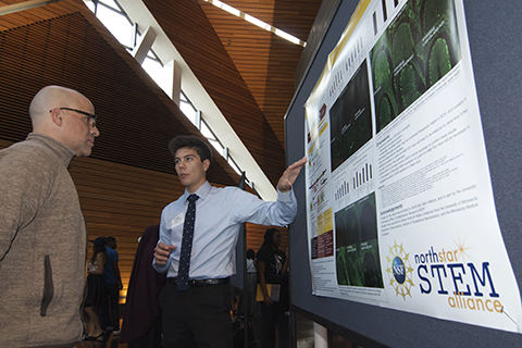 A student presents research to a visitor at the North Star STEM Alliance Kickoff
