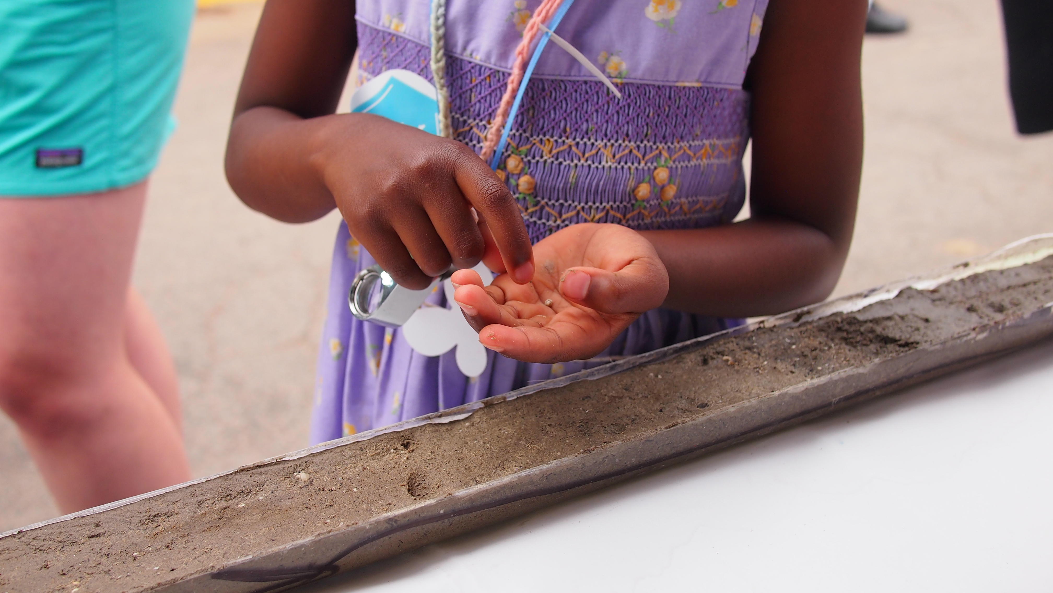 A child's hands hold sediment from the core in front of her