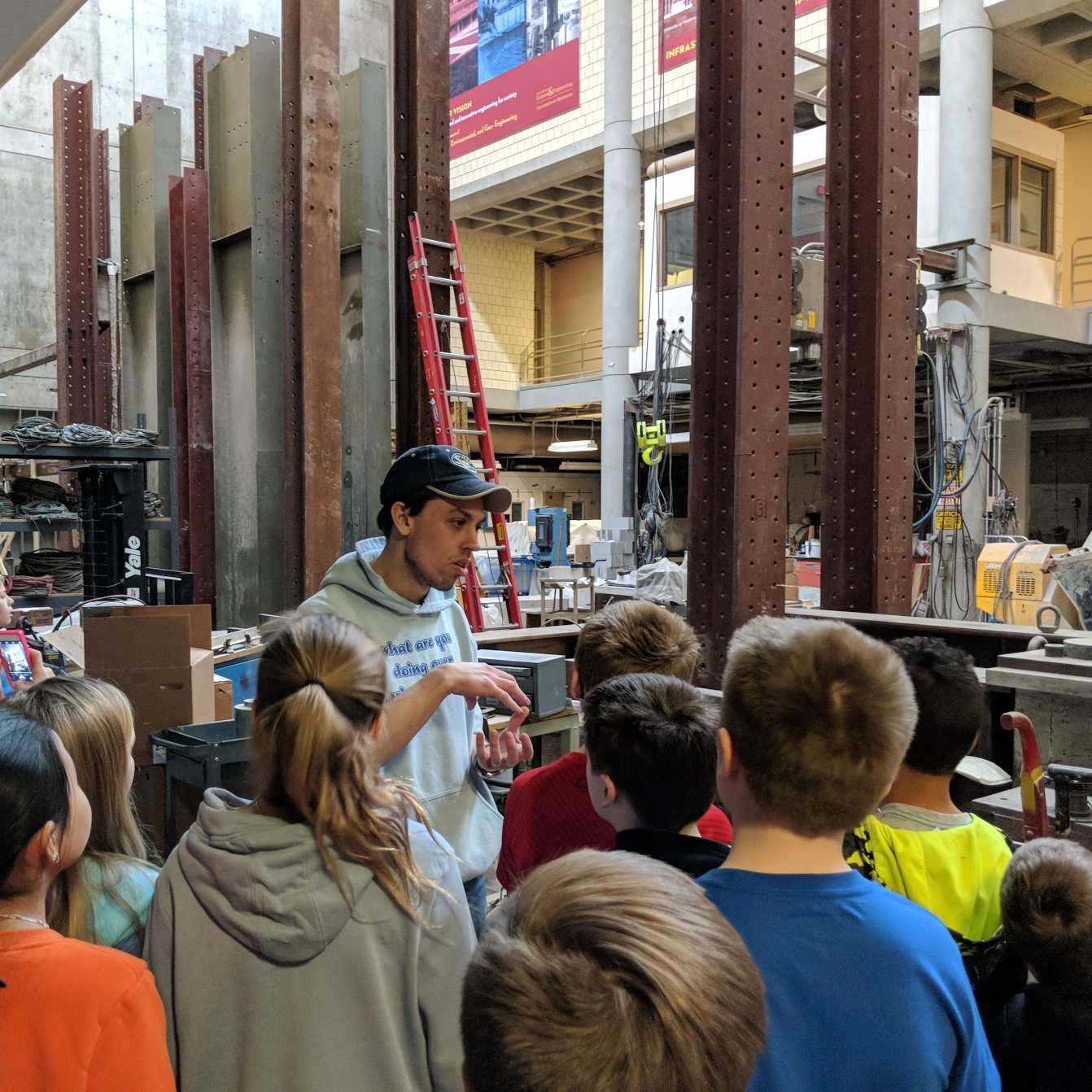 Graduate student explains structural research to visiting middle school students.