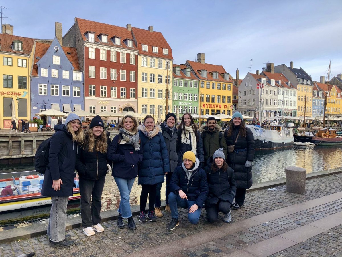 A group of people smiling for a photo by a canal in the city.