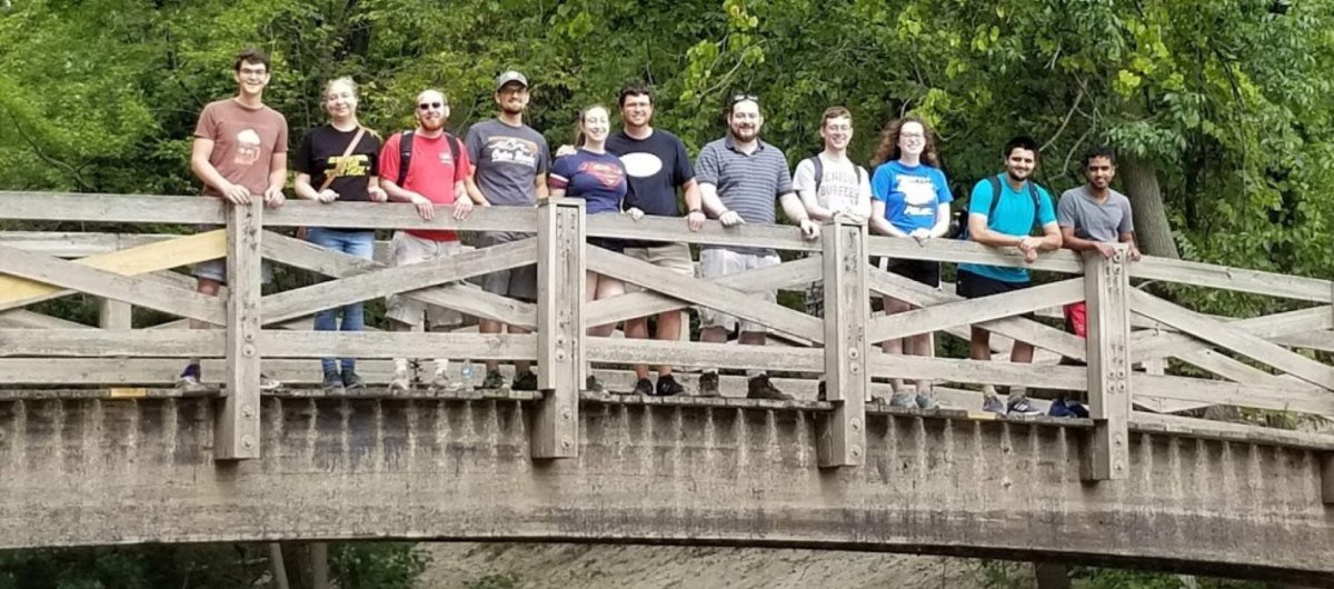 A group of happy students on a bridge with trees in the background