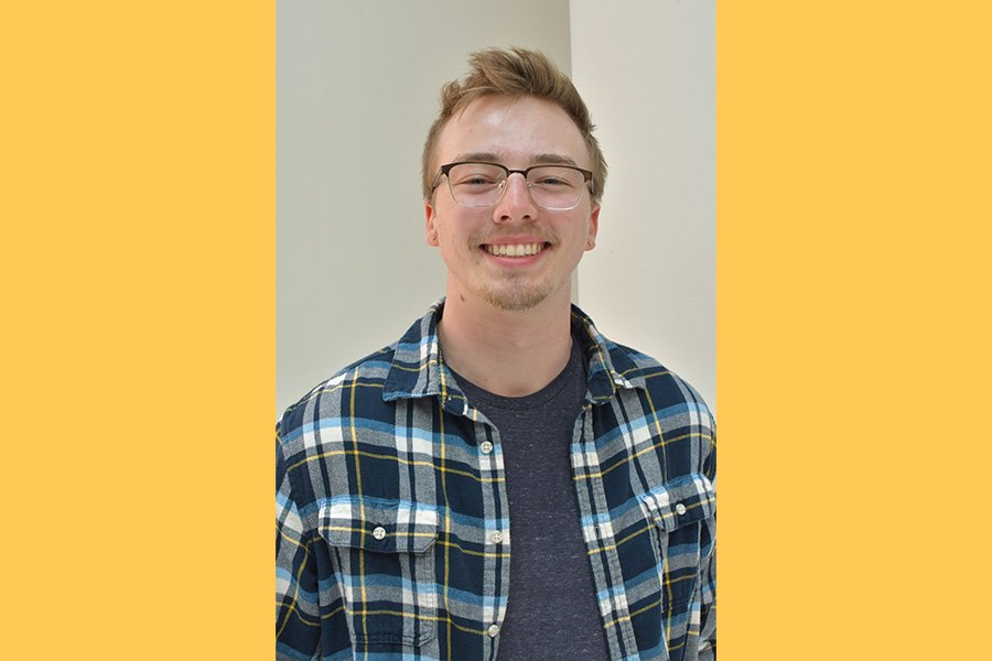 Nick Kruegler, smiling wearing glasses and a flannel shirt