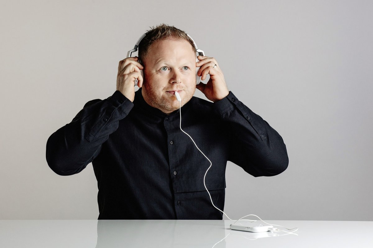 A man with white headphones and the Lenire device in his mouth.