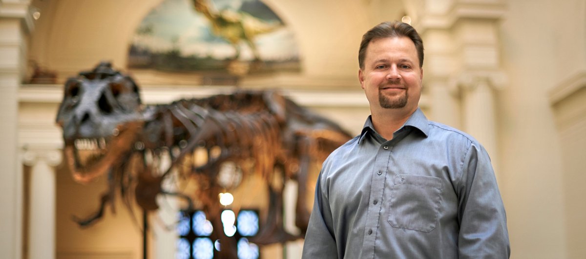 Professor Peter Makovicky standing in front of a dinosaur at the Field Museum in Chicago.