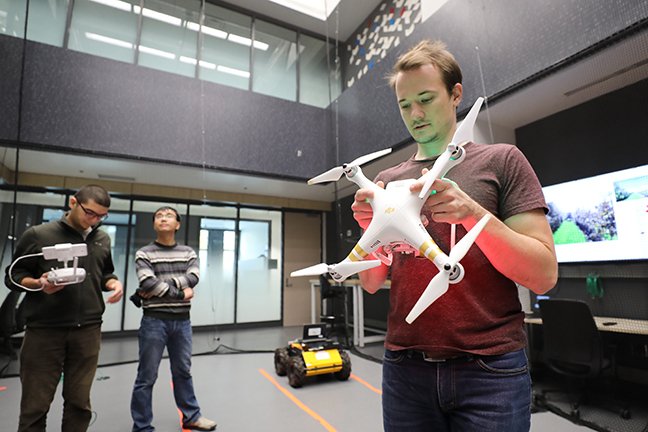 Grad students holding aerial robots in the two-story lab