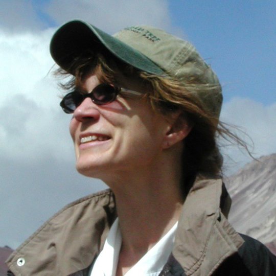 Smiling woman outdoors wearing sunglasses and a baseball cap
