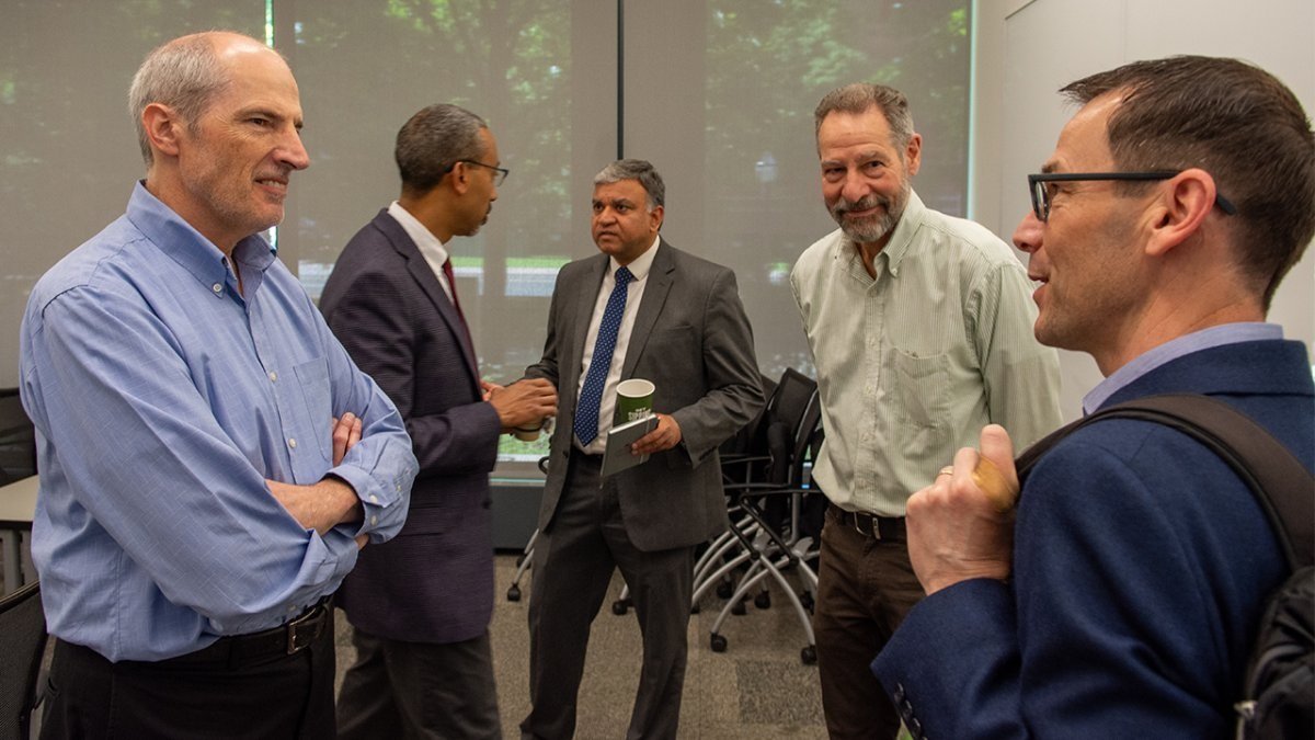 Steve Koester on the left in a blue shirt in conversation with other University officials