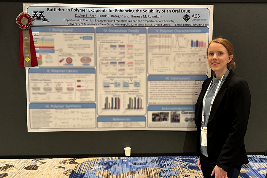 A photo of Ph.D candidate Kaylee Barr and standing next to her award winning research poster. A ribbon is pinned to the corner of the poster.
