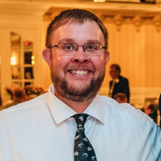 Smiling man with glasses and beard in a shirt and tie