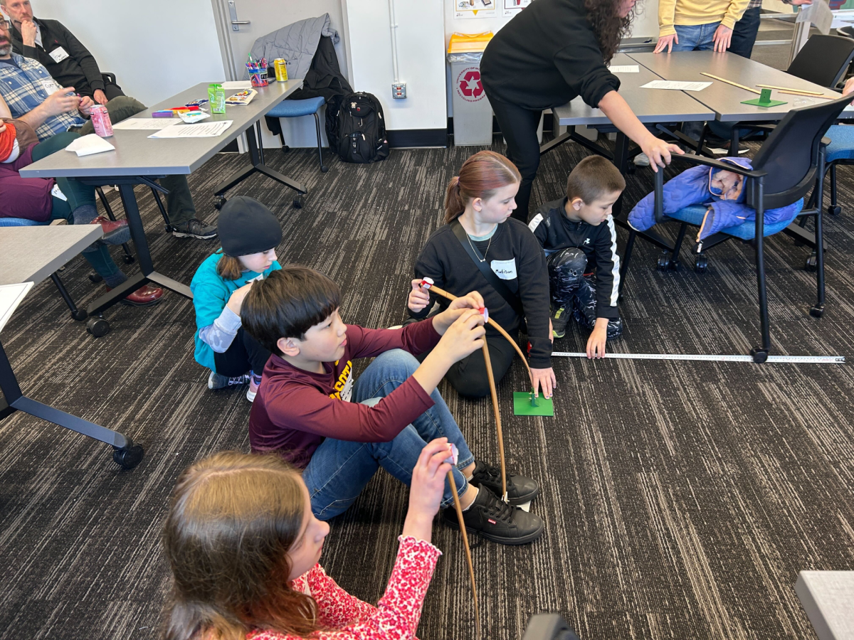 children sitting on floor next to their self-made catapults