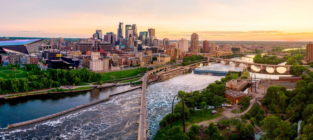 Sunset photo of St. Anthony Falls on the Mississippi River, with the Minneapolis skyline to the left and St. Anthony Falls lab on the right