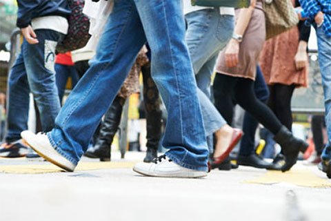 People walking on sidewalk showing feet to knees