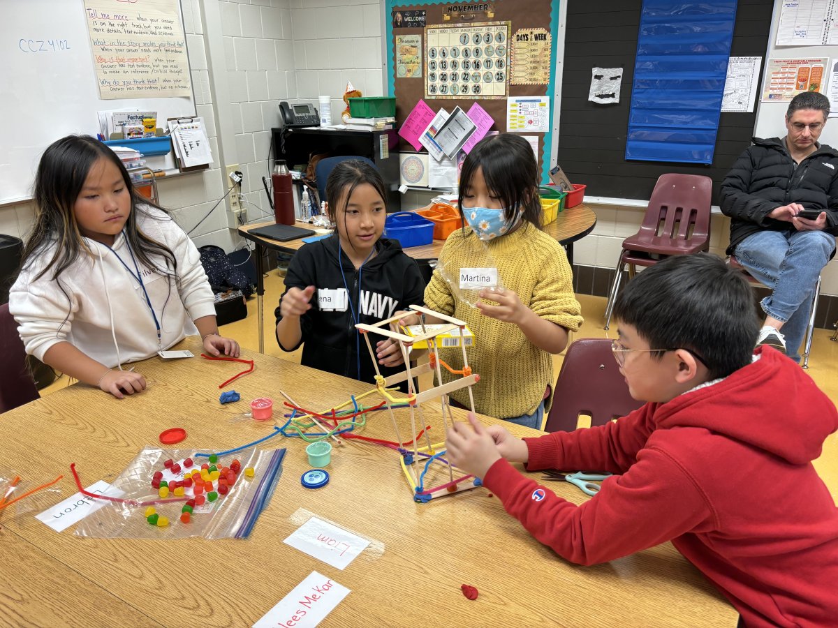 Children gathered around a table building a tower 