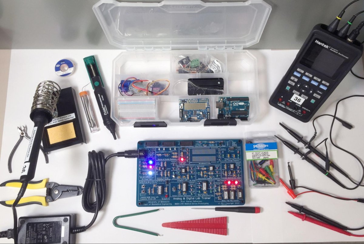 The home lab box contains the trainer board, soldering and assembly tools, power supply, part organizer, and handheld combination oscilloscope, function generator, and multimeter.