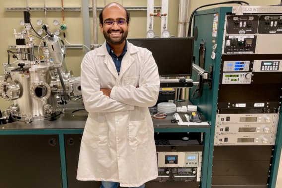 Karthik Srinivasan standing in lab in front of equipment