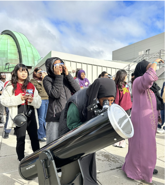 Students in Rooted in STEM program looking through a telescope