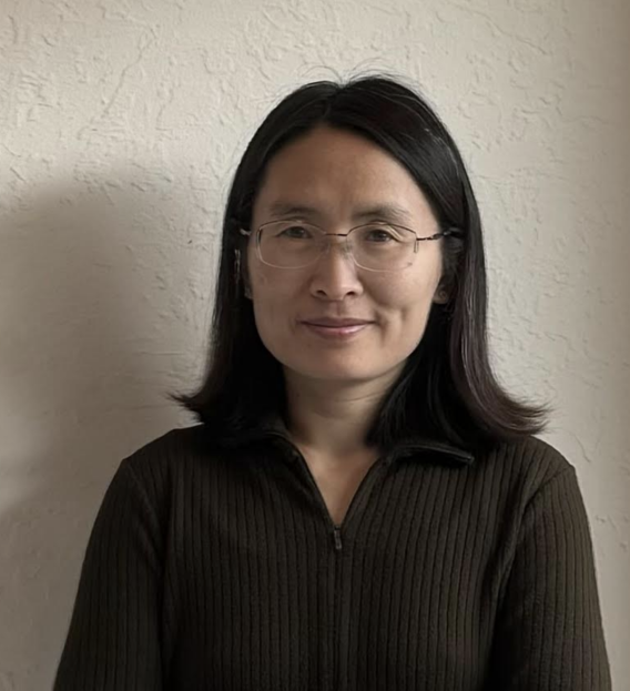 headshot of asian woman in a dark shirt against a gray wall